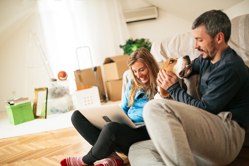 man woman and beagle sitting on the floor next to moving boxes